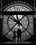 A man and woman look out at the city through a large clock at the Musee d'Orsey.  Paris, France.